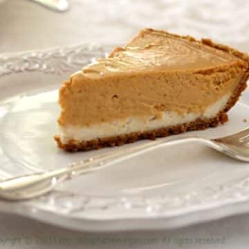 vegan pumpkin cheesecake on white plate with silver fork holiday table thanksgiving dessert