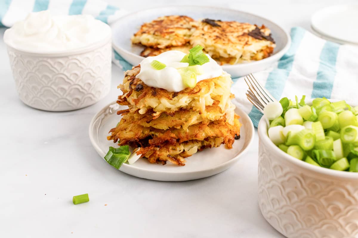 stack of vegan potato pancakes on plate neat bowls of toppings and more pancakes