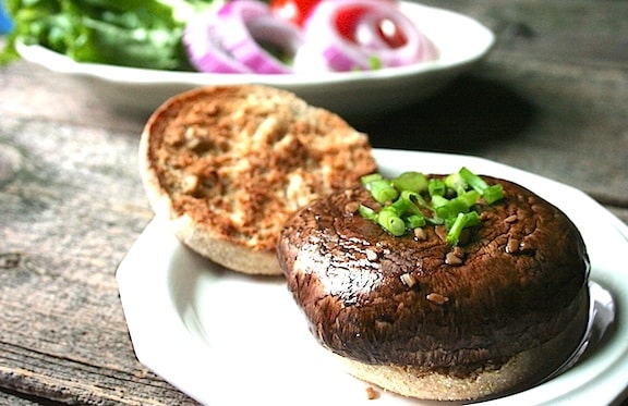 Easy Portobello burgers on a plate next to bowl of toppings