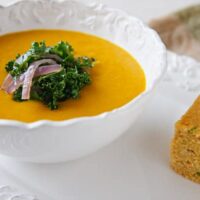 coconut butternut squash soup with fresh kale and onion garnish and cornbread side