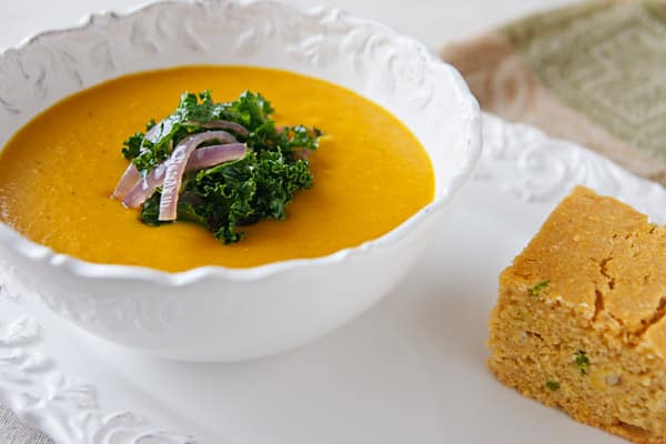 coconut butternut squash soup with fresh kale and onion garnish and cornbread side