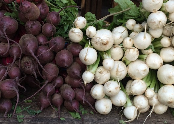 White turnips and red beets piled at a farm market
