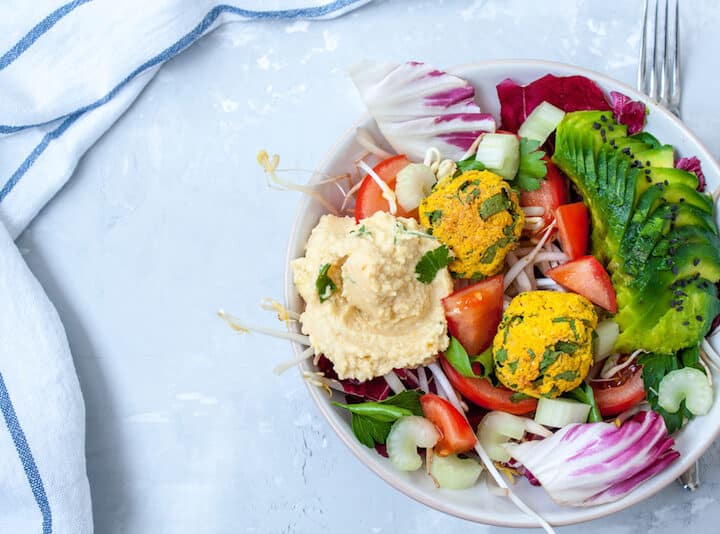 Vegan salad with falafel, hummus, vegetables. View top on gray concrete background. Vegan Food Concept.