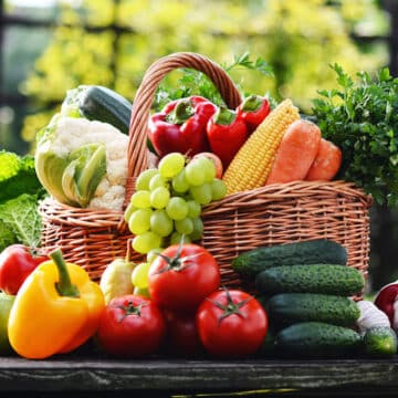 Wicker basket with assorted raw organic vegetables in the garden.