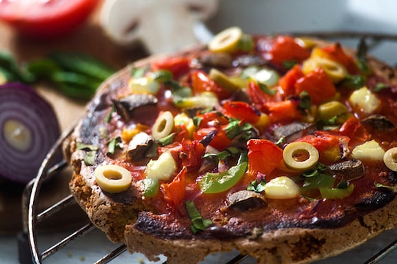 Gluten-free quinoa pizza crust or flatbread covered with toppings on a grill