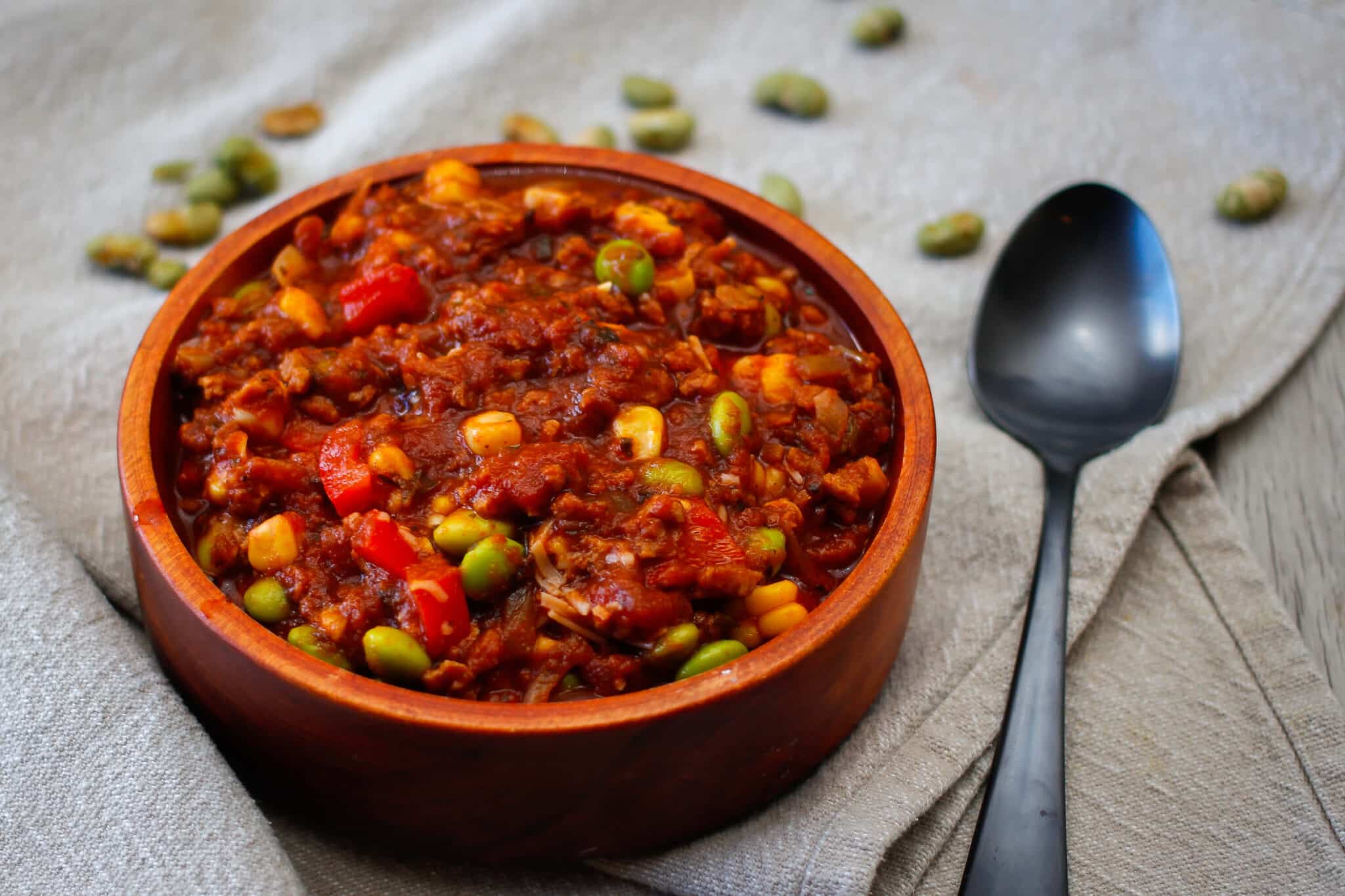 vegetarian chili with corn and soy beans in an orange bowl