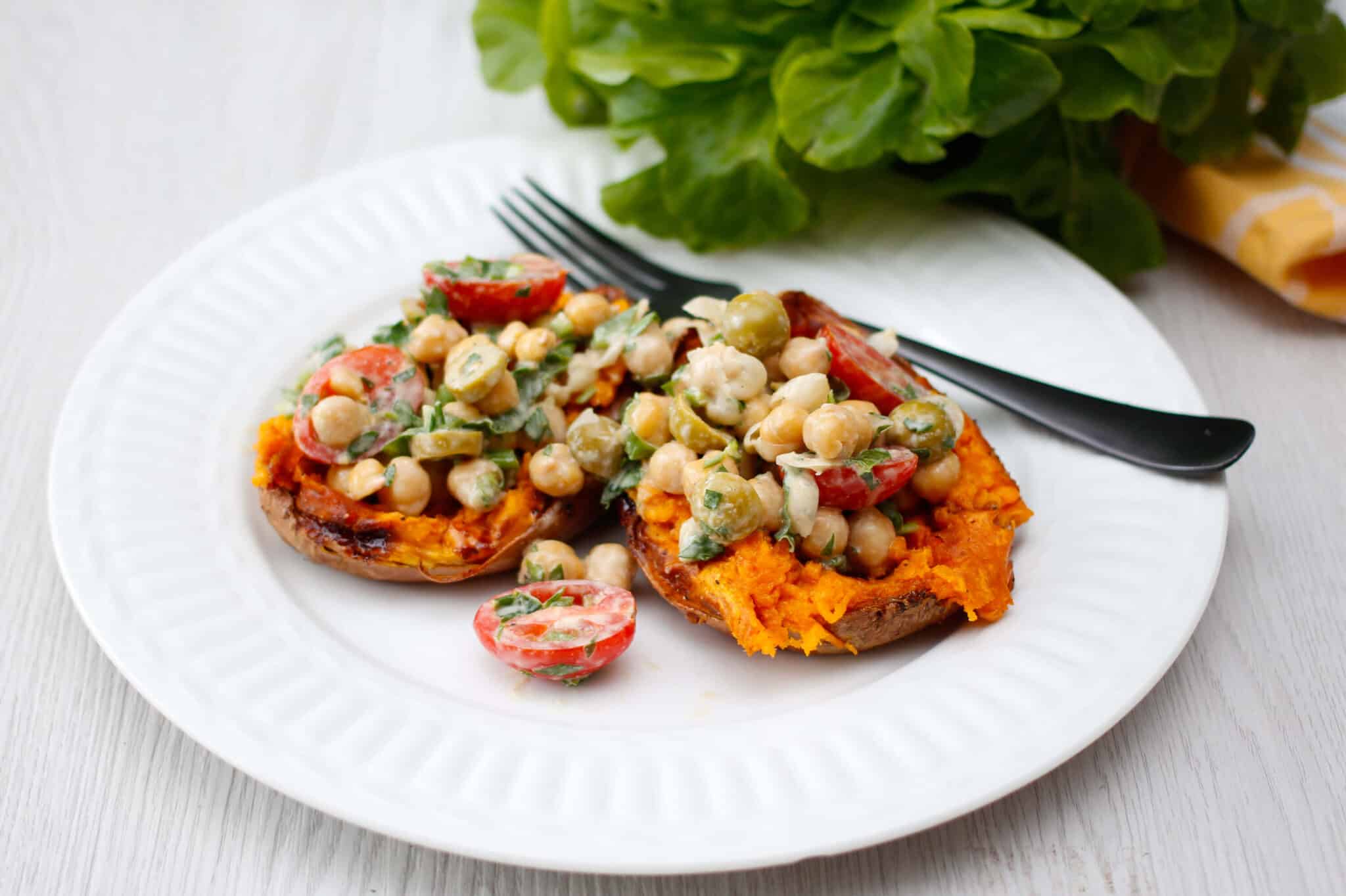Sweet potatoes stuffed with spicy chickpeas and tahini on a plate