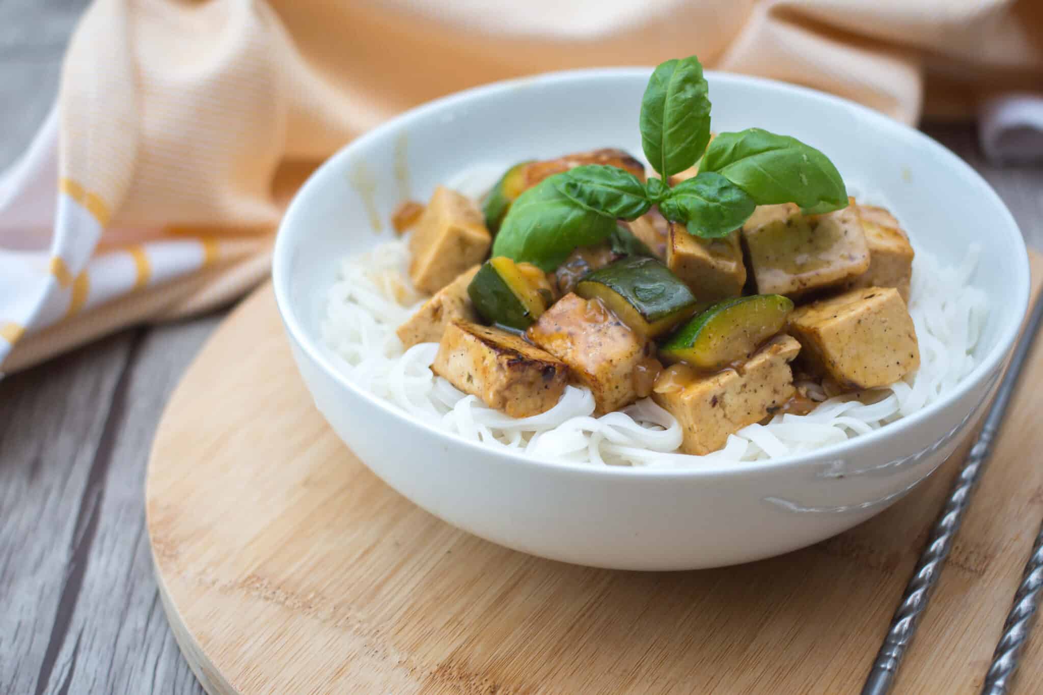 tofu casserole topping rice noodles in a bowl next to chopsticks