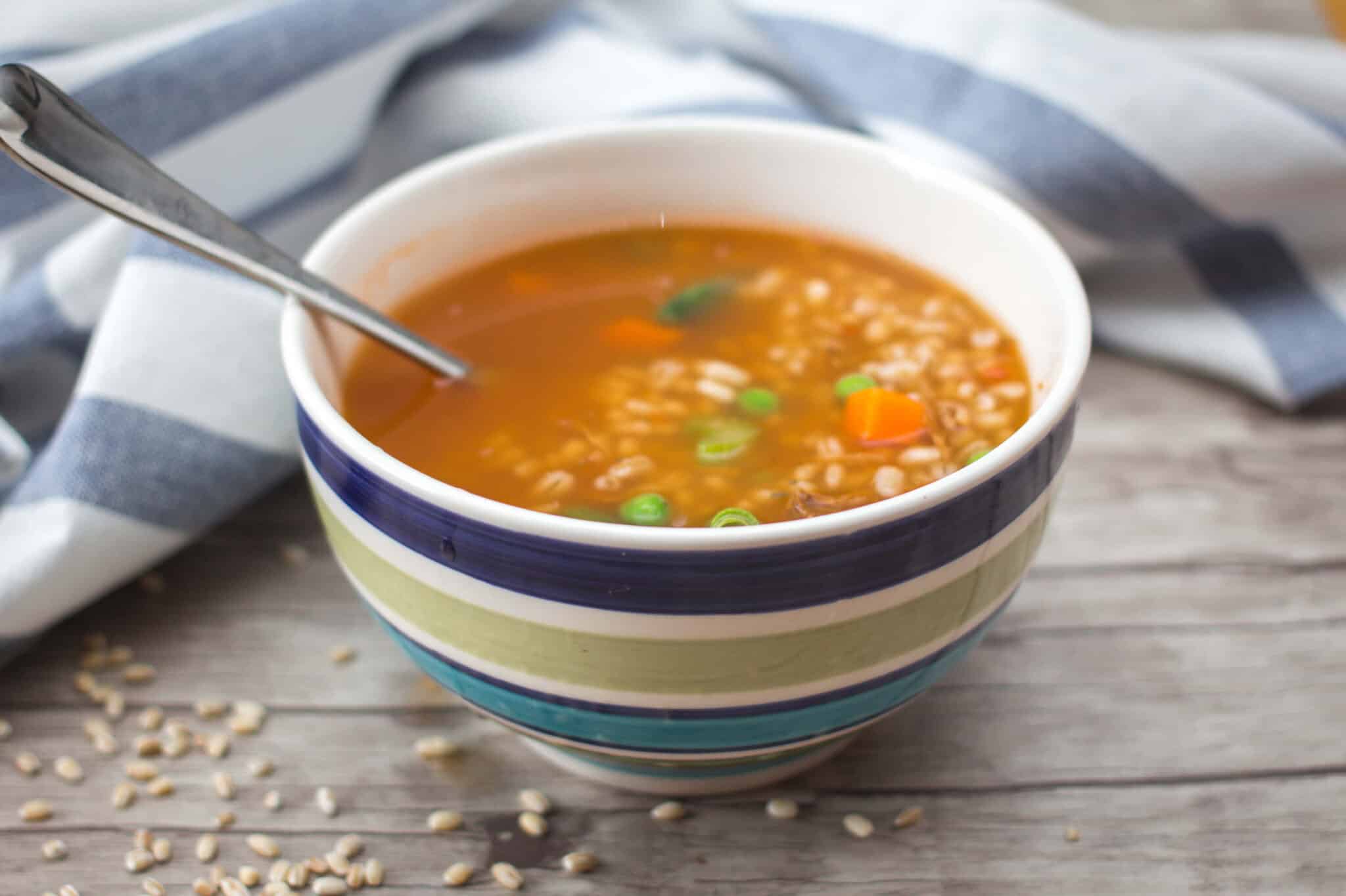 blue striped bowl of vegetable and barley soup on a table