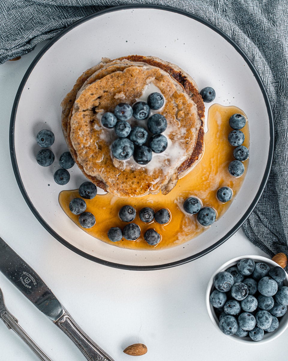 vegan almond flour pancakes on a plate with syrup and blueberries