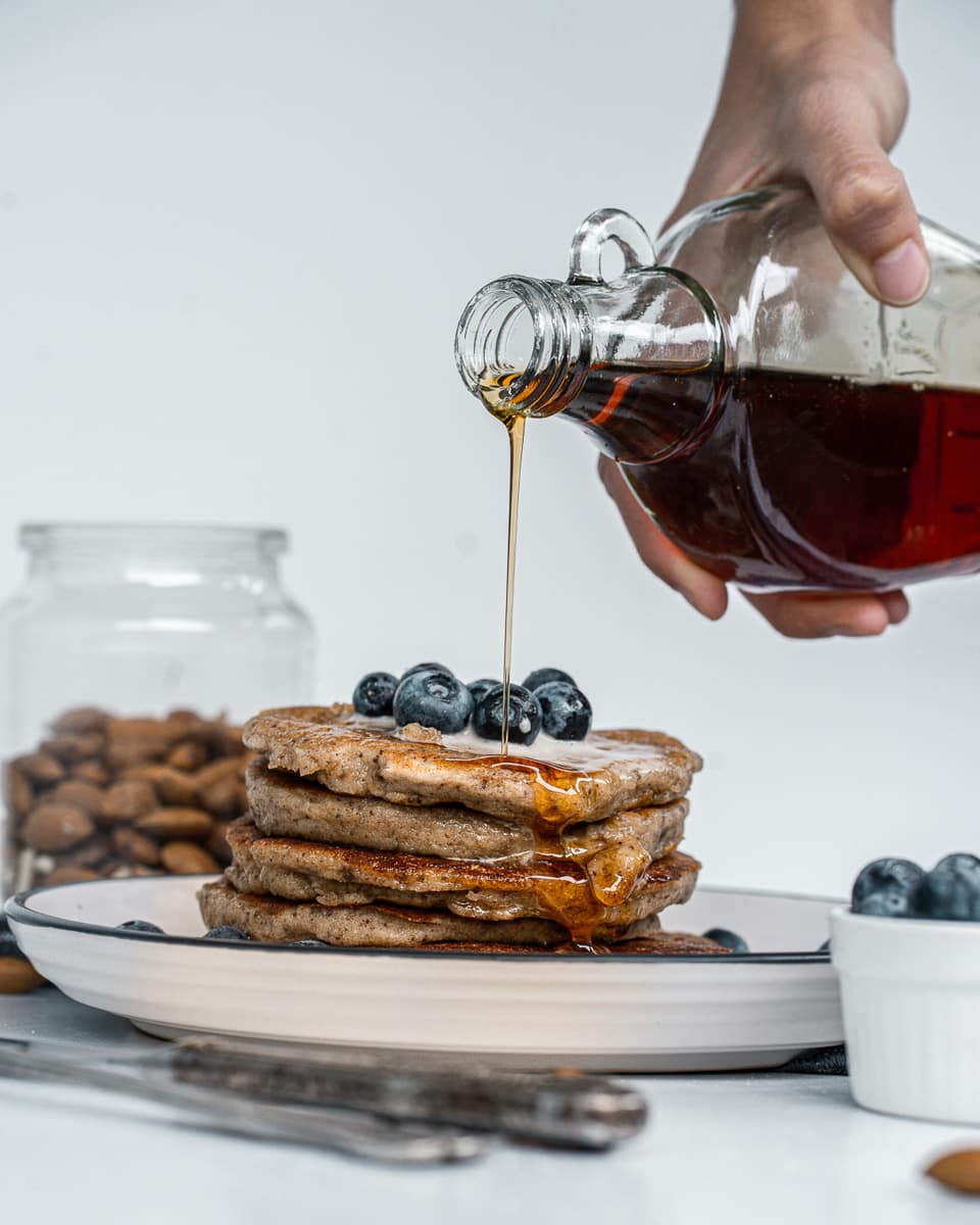 pouring syrup over vegan almond flour pancakes
