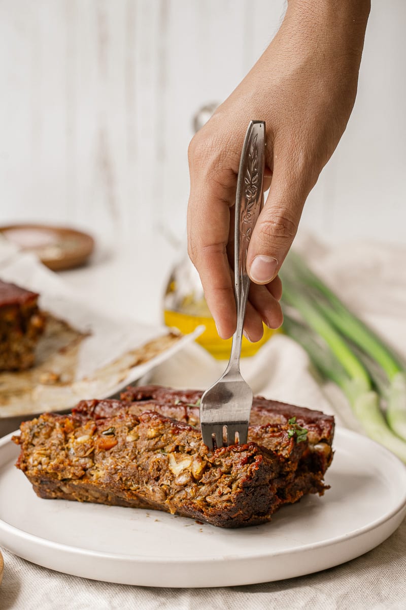 taking a forkful of vegan lentil meatloaf