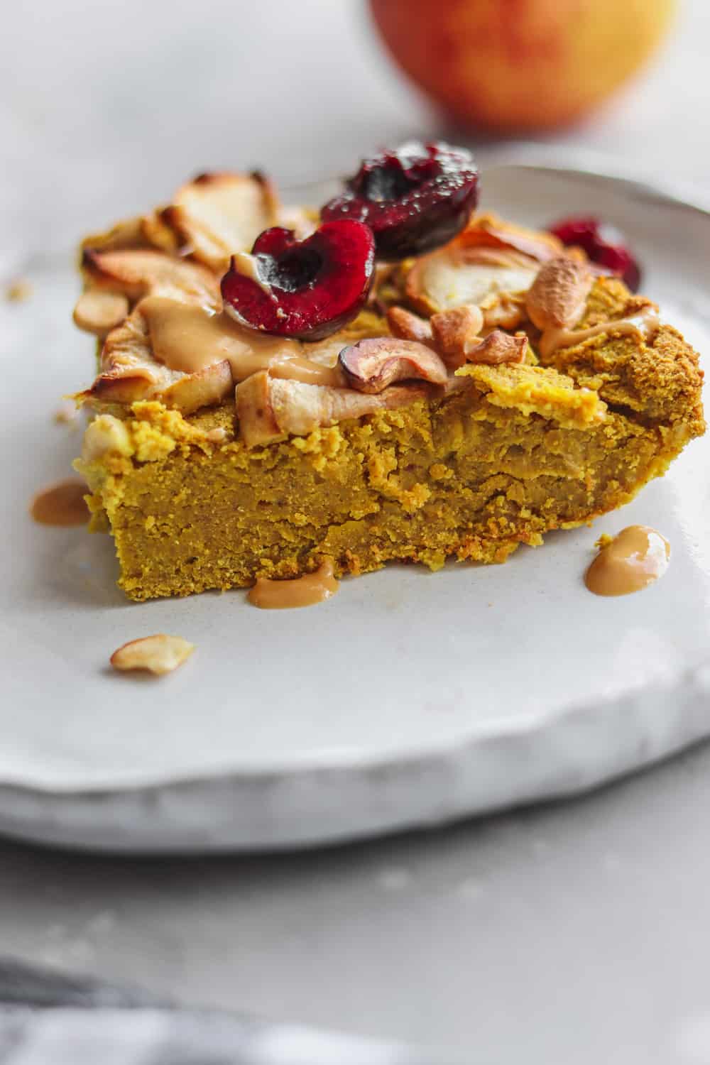 slice of chickpea cake topped with fruit and nuts