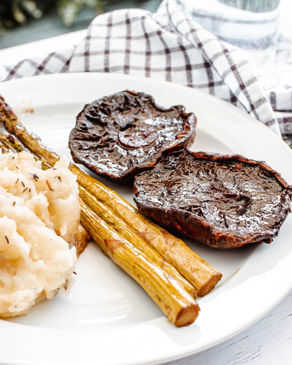 portobello mushroom steaks on a plate with mashed potatoes and asparagus