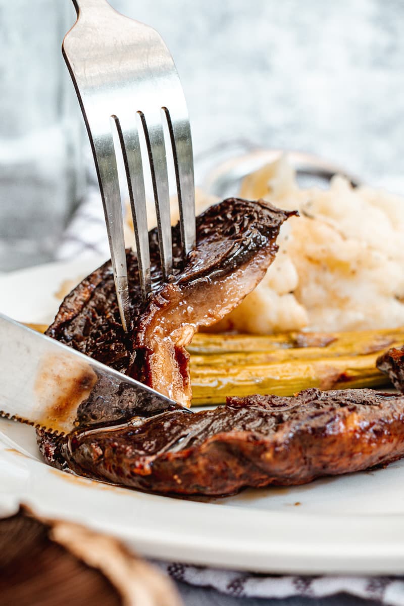 fork and knife cutting into a portobello mushroom steak