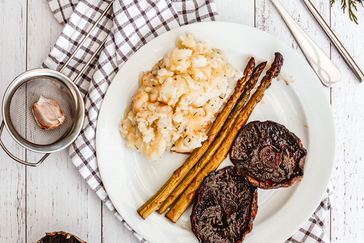 plate of vegan mashed potatoes with asparagus and portobello steaks