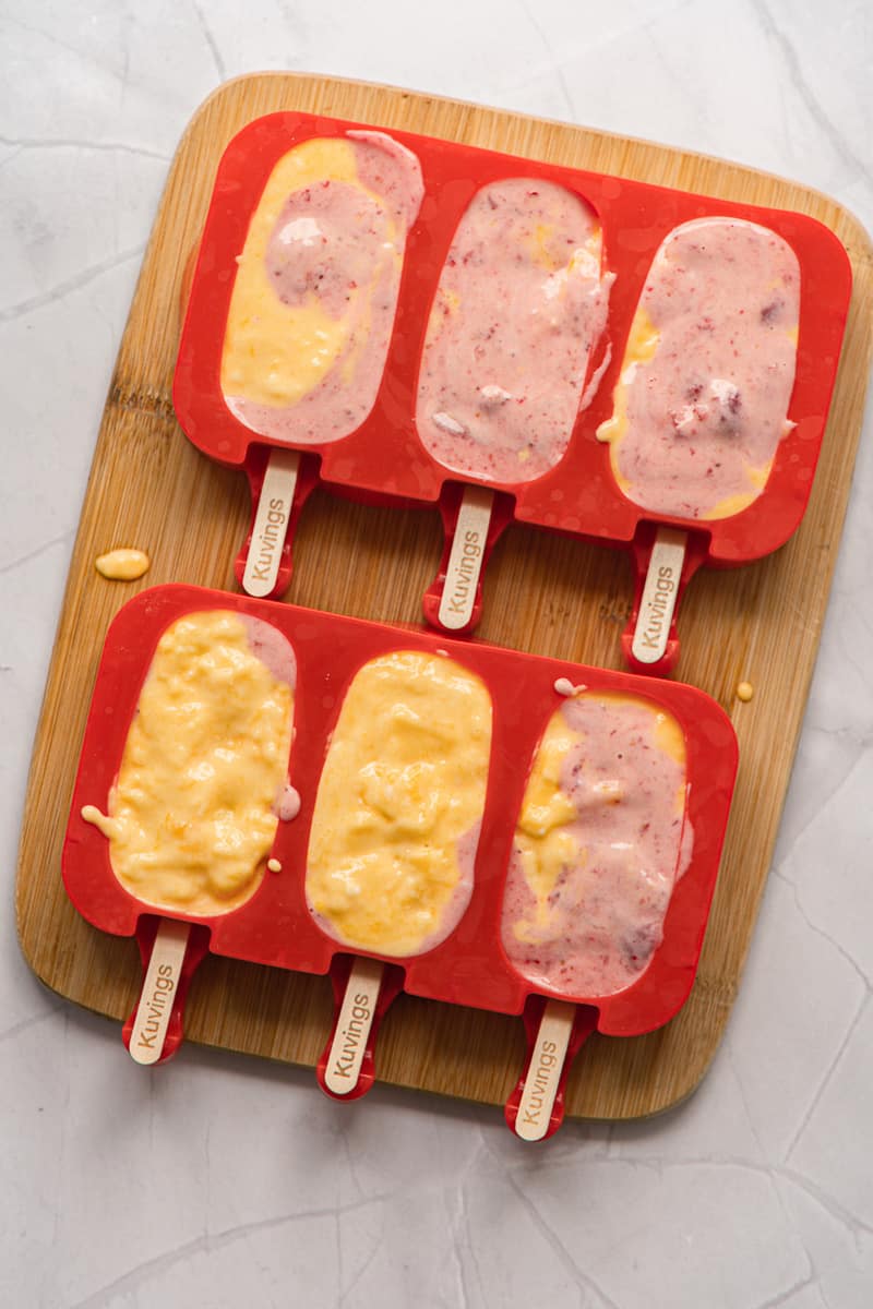 molds full of vegan strawberry mango popsicles mixture