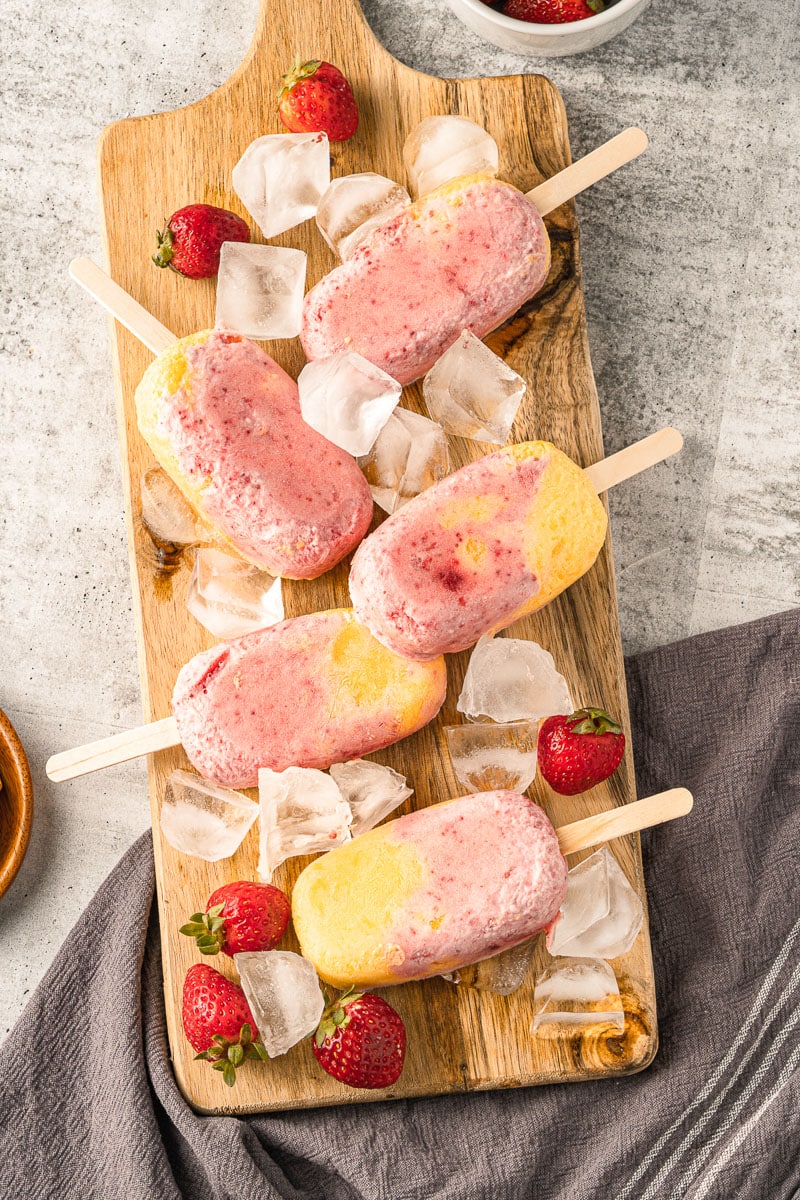 vegan strawberry mango popsicles on a wooden tray