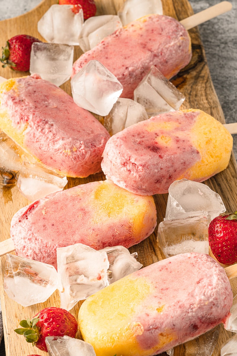 close up vegan strawberry mango popsicles clustered on tray