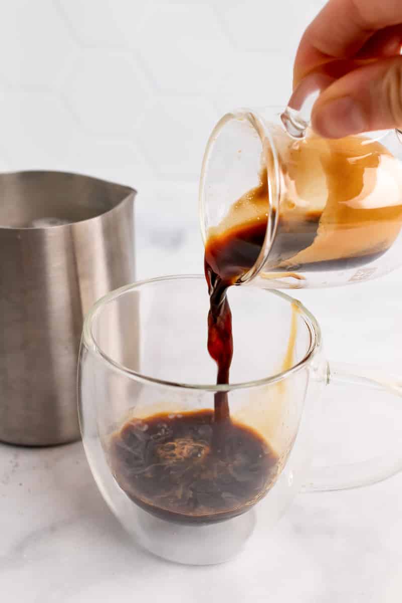 pouring espresso into glass for oat milk latte