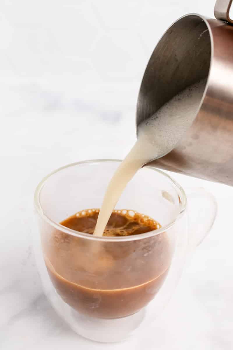 pouring oat milk into glass for oat milk latte