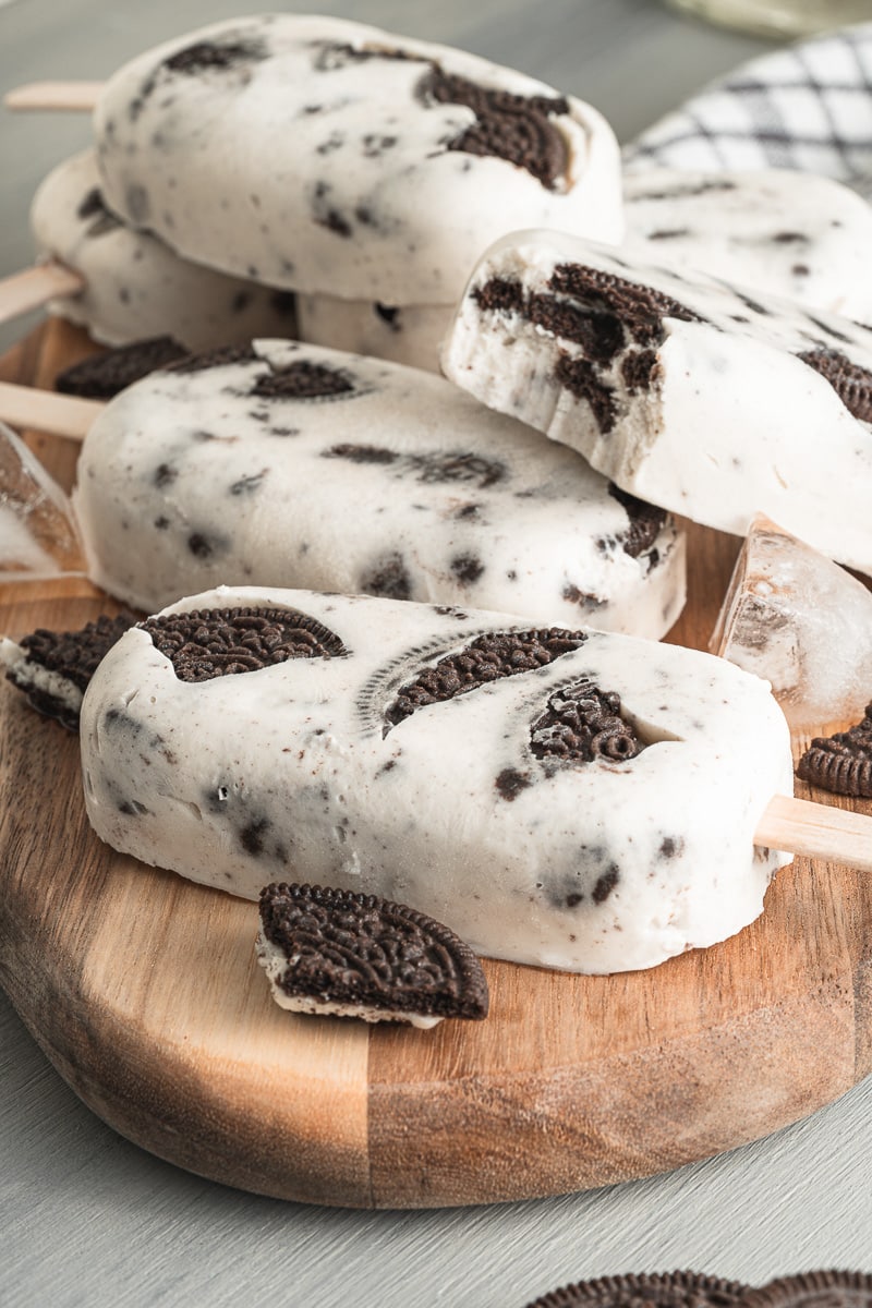 close up cookies & cream vegan popsicles stacked on wooden serving tray