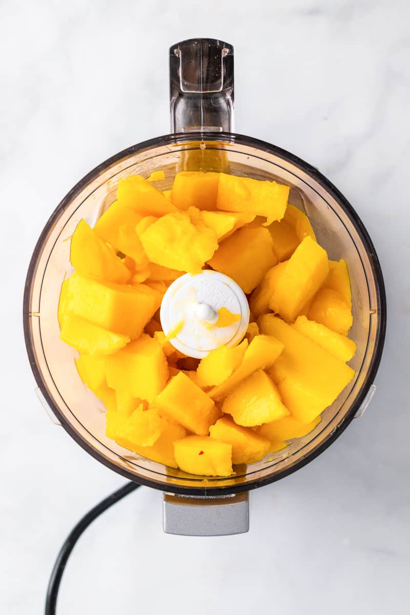 food processor full of mango chunks for vegan mango ice cream