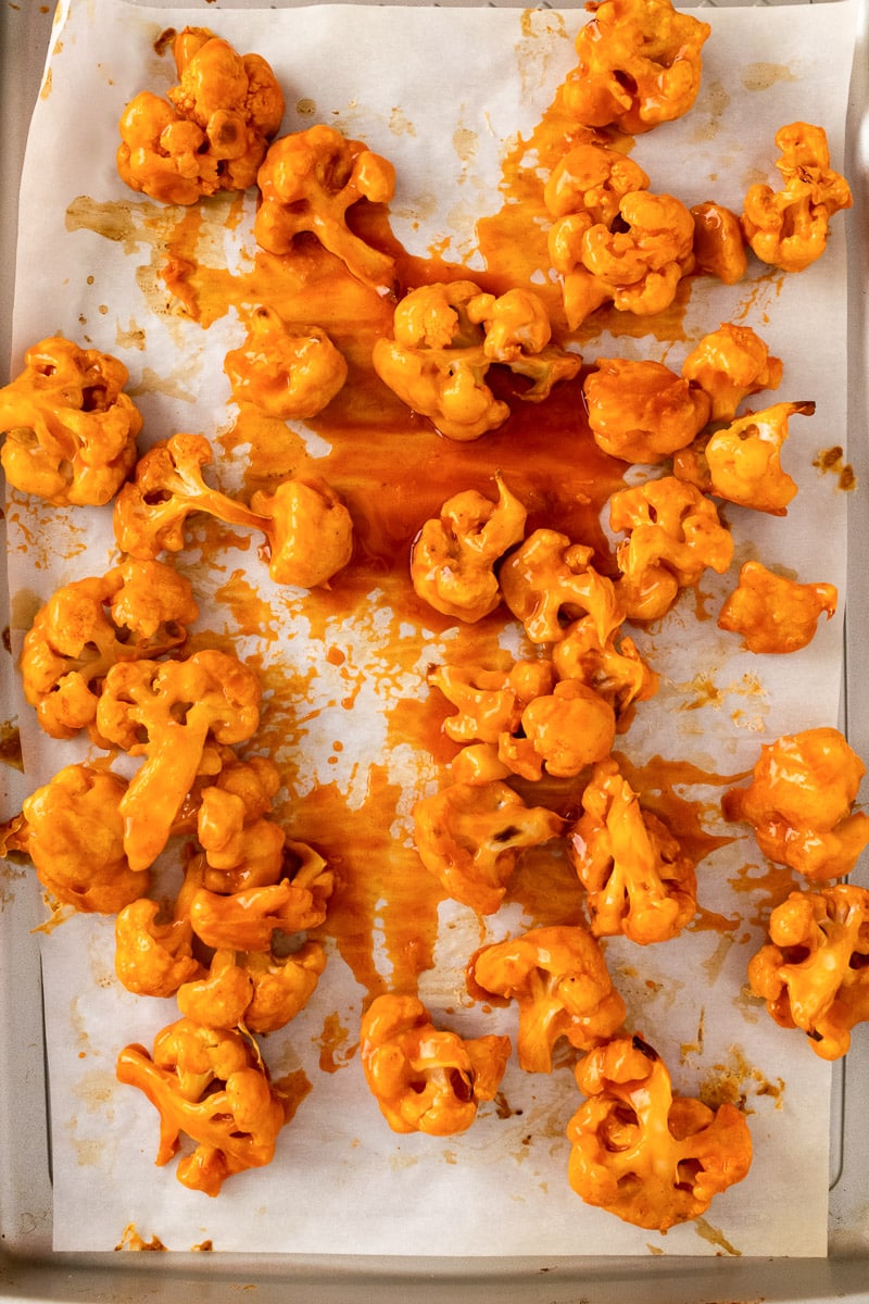 vegan buffalo cauliflower florets on baking sheet with sauce