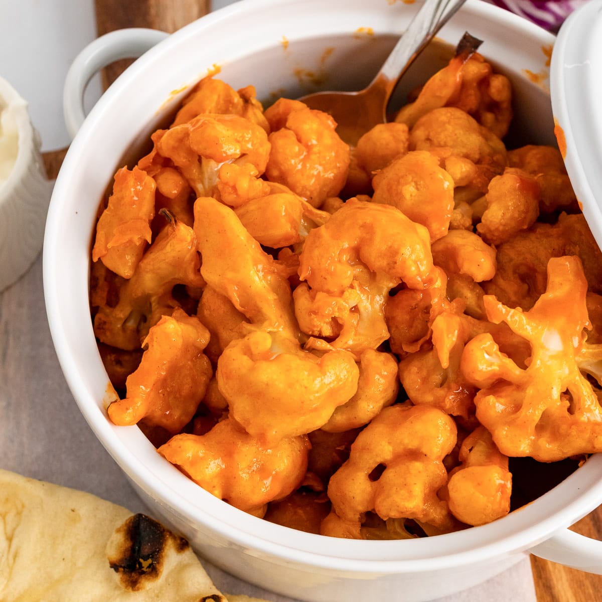 close up white pot of vegan buffalo cauliflower with spoon