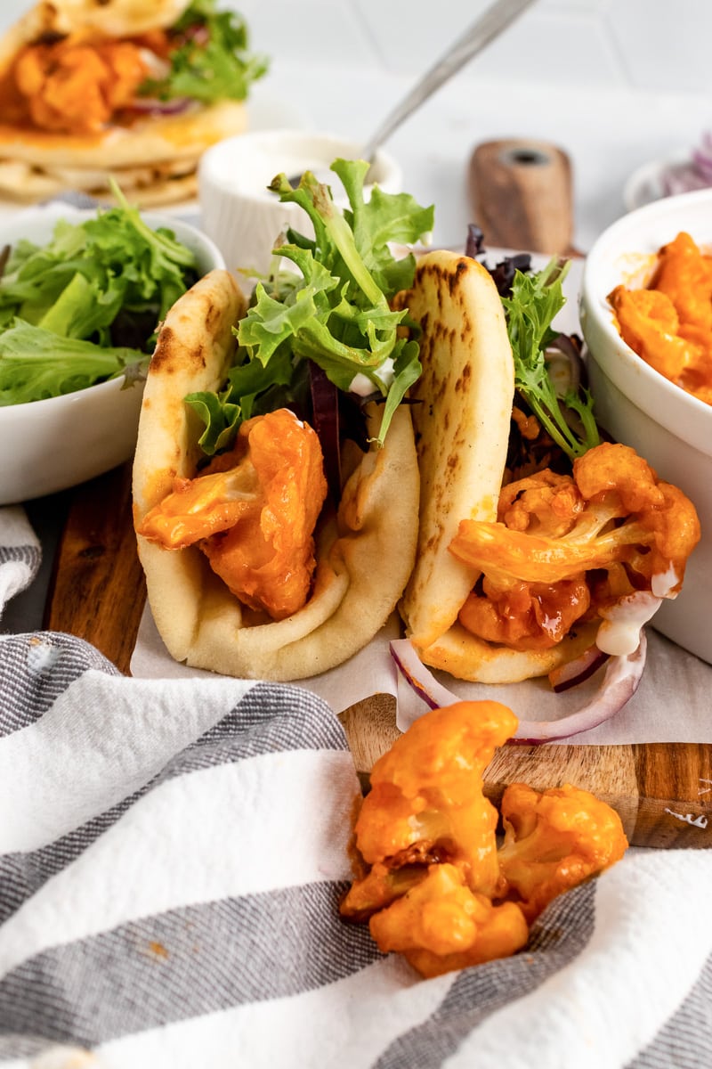 tall two buffalo cauliflower wraps between bowl of lettuce and bowl of buffalo cauliflower