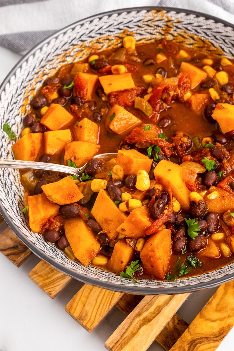 close up bowl of sweet potato black bean chili with metal spoon