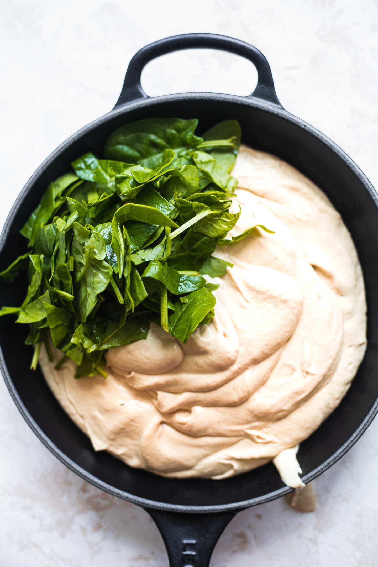 Artichoke dip and spinach in a skillet