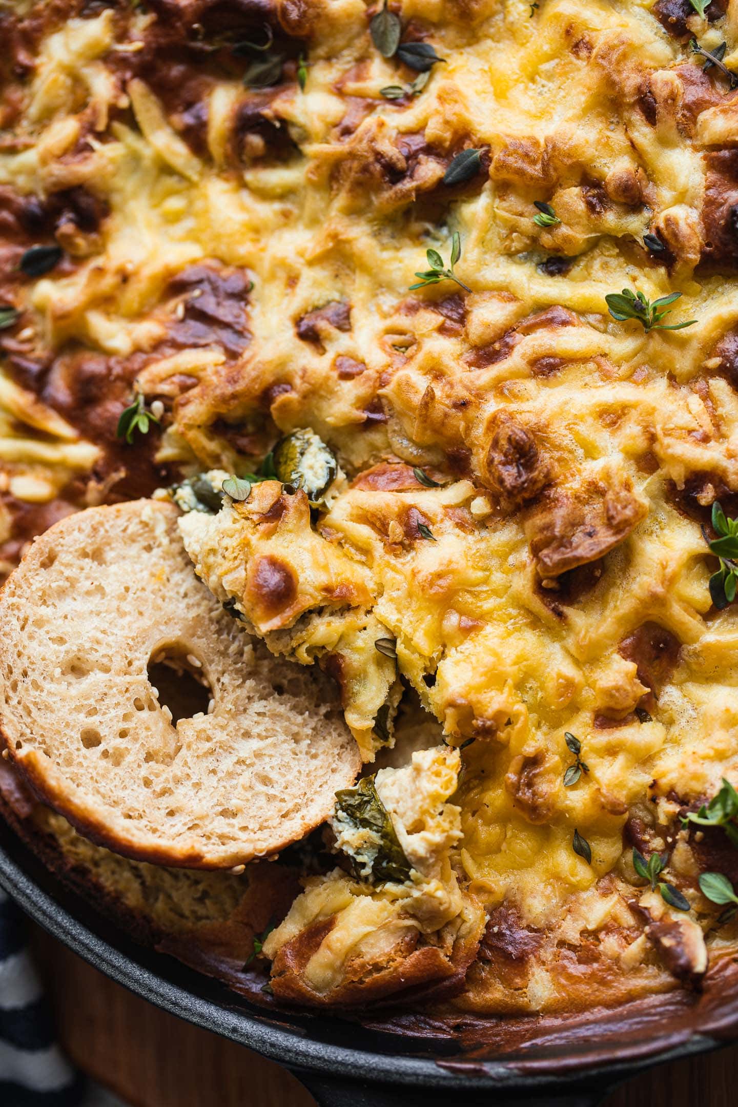 Bagel being dipped into a cheesy vegan dip