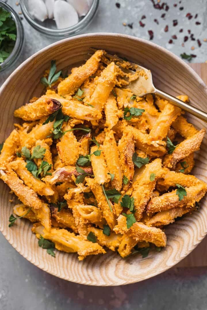 Cheesy vegan pasta in a bowl with fresh herbs and breadcrumbs
