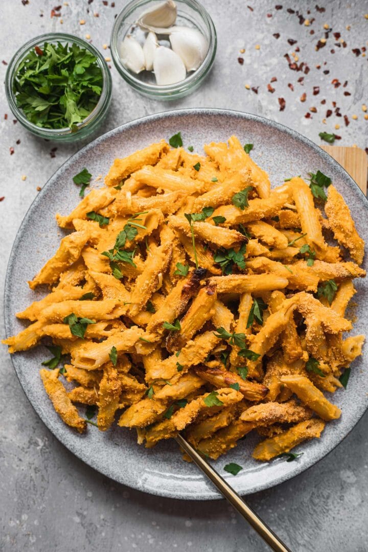 Dairy-free mac and cheese with breadcrumbs and fresh herbs on a plate