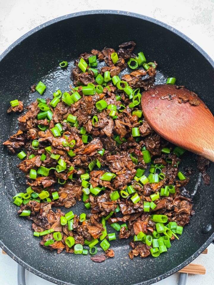 Porcini mushrooms and scallions in a frying pan