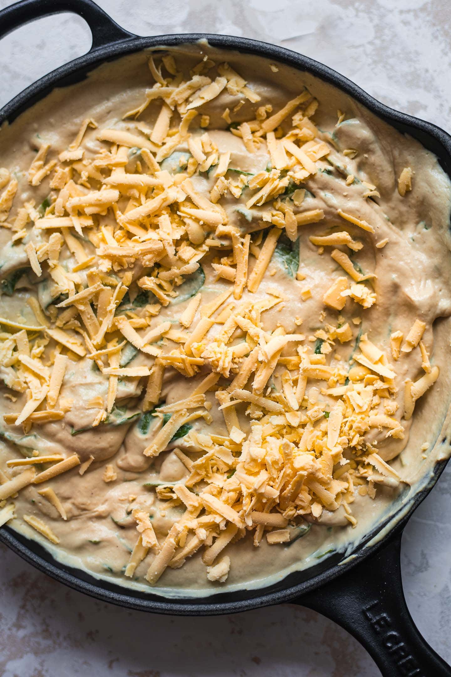 Vegan cashew dip with grated cheese in a cast iron skillet