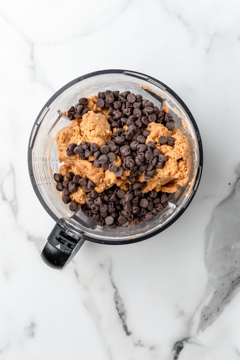 Chocolate chips added to chickpea cookie dough in the food processor bowl