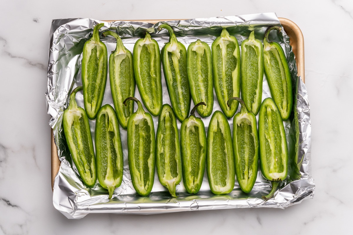 arranging the cored and seeded jalapeno peppers on t a baking sheet