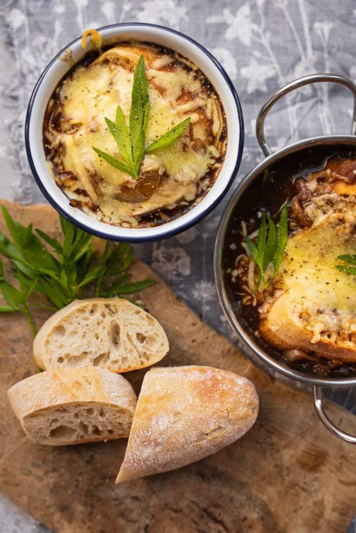 Two bowls of cheesy vegan soup with baguette