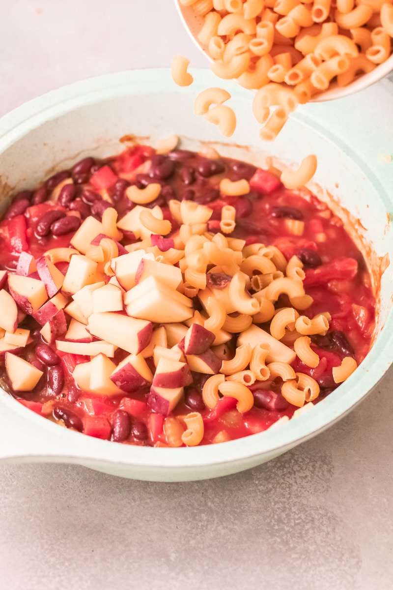 pouring pasta into Minestrone Soup