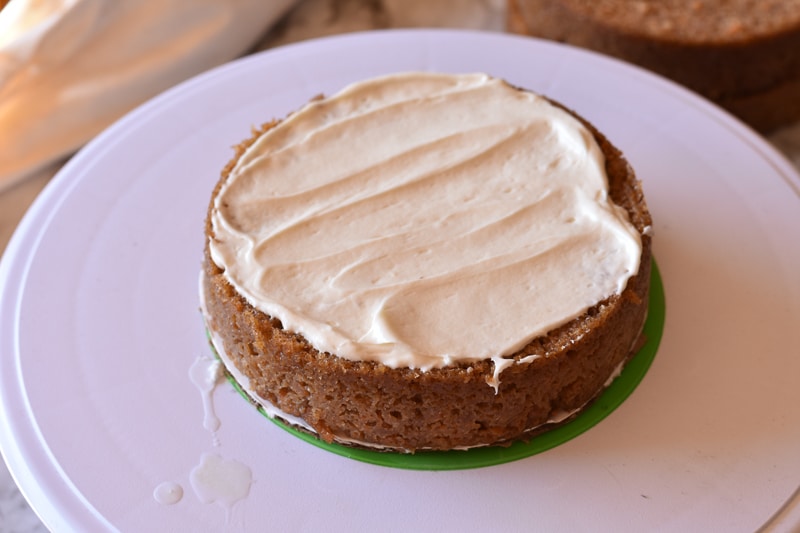 spreading cream cheese frosting on vegan carrot cake