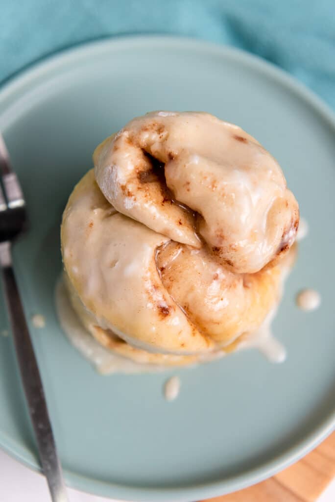 Vegan cinnamon roll on a blue plate with a fork
