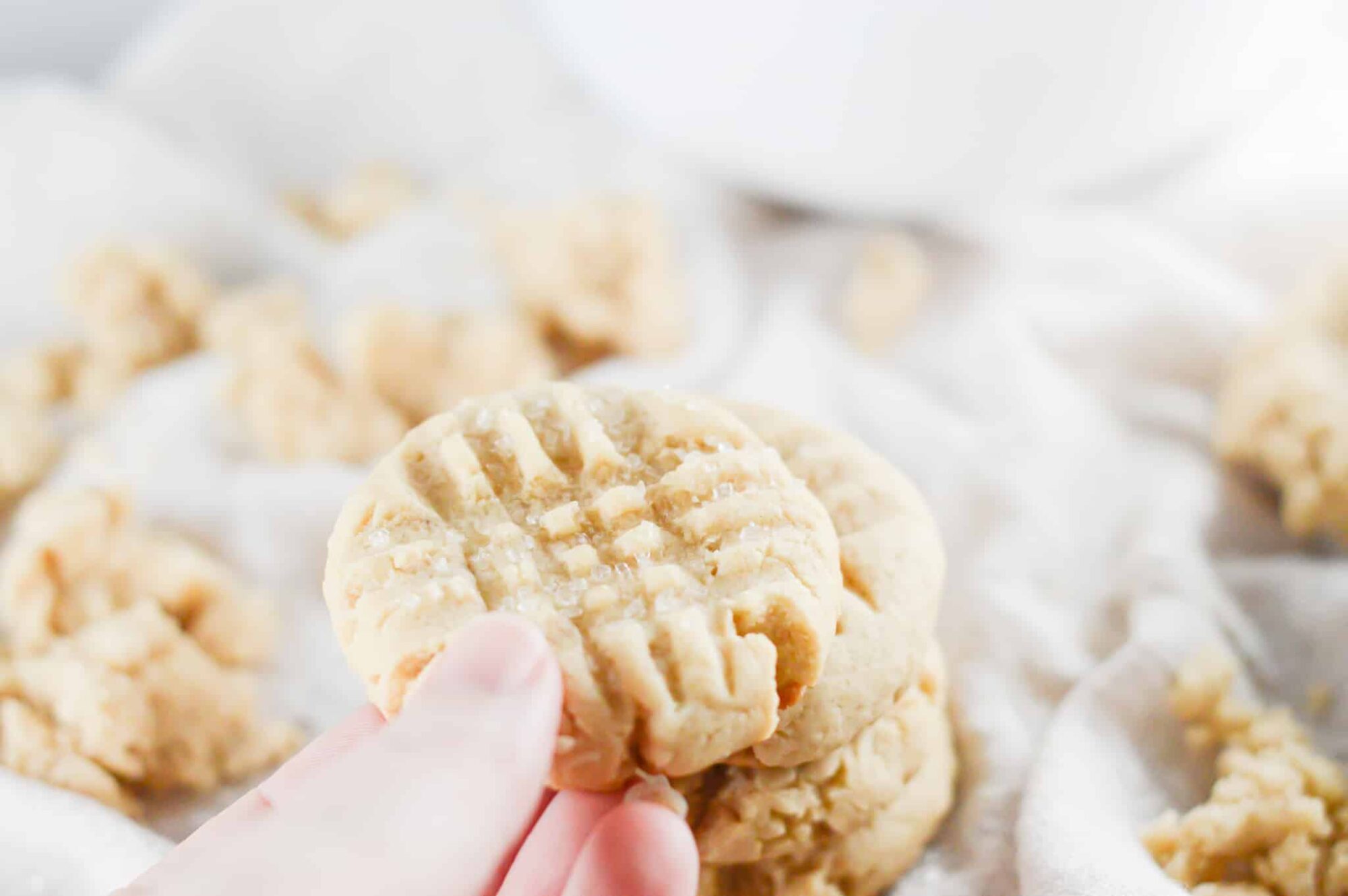 hand grabbing a cookie from a stack of vegan sugar cookies