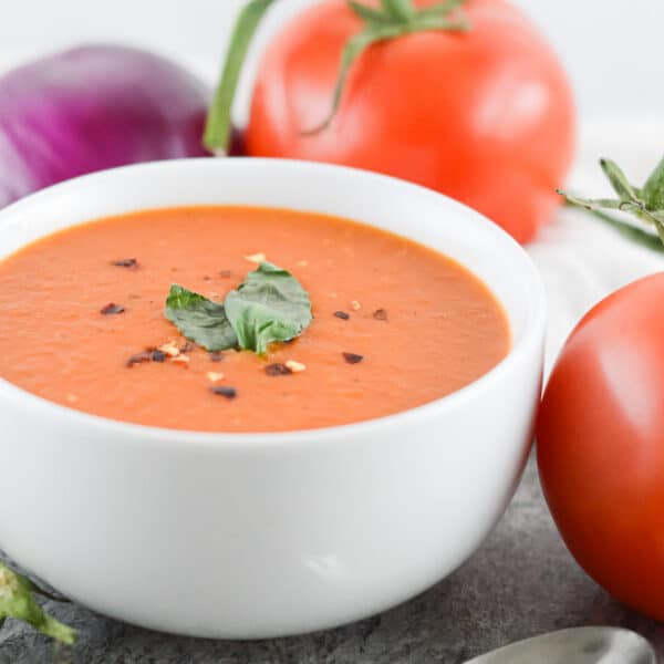 closeup of vegan tomato soup with tomatoes in the background