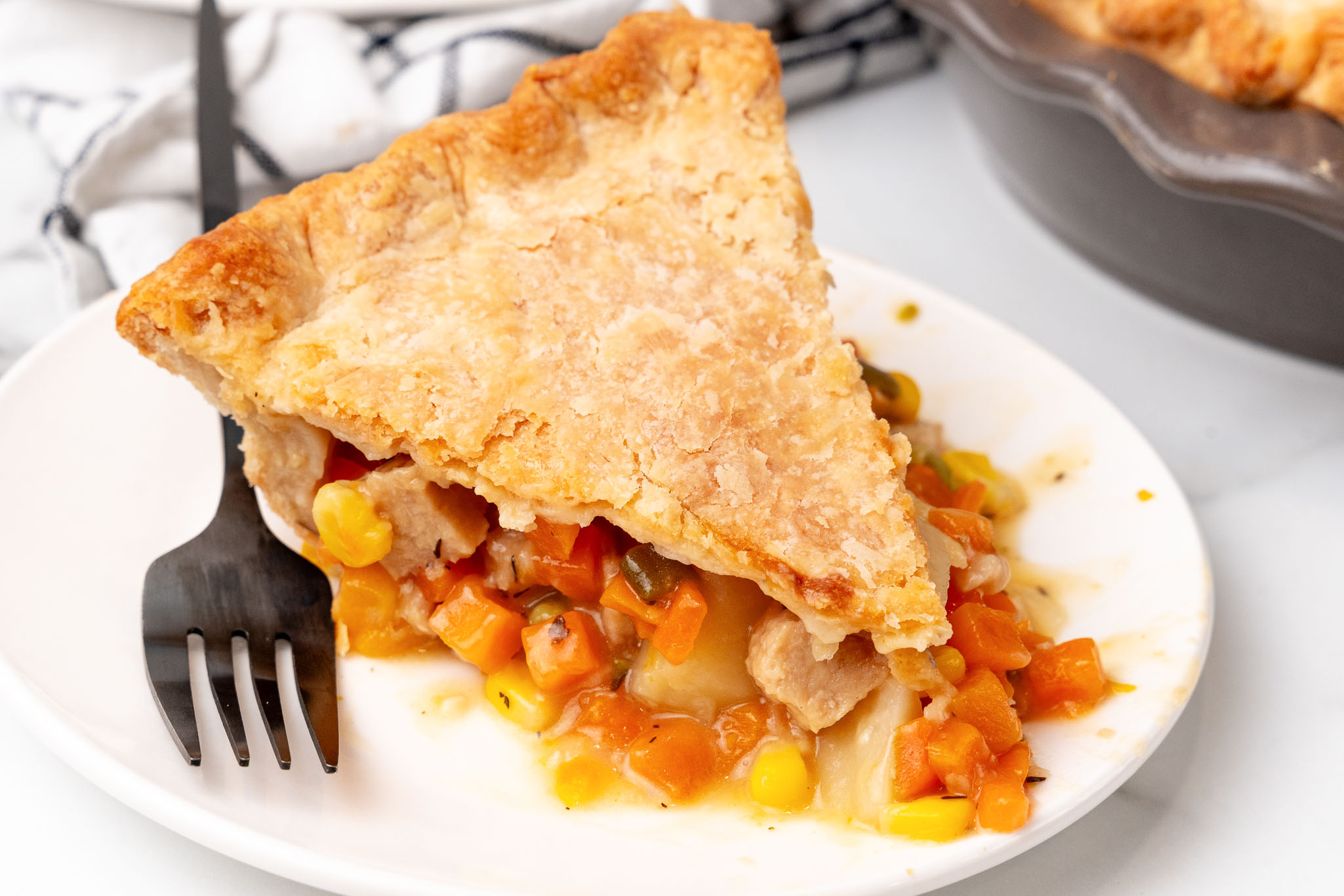 Slice of vegan pot pie showing carrots, corn, potatoes and vegan chicken under a flaky crust