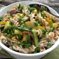 Vegan pasta alfredo with asparagus, peas, yellow squash, and sun-dried tomatoes