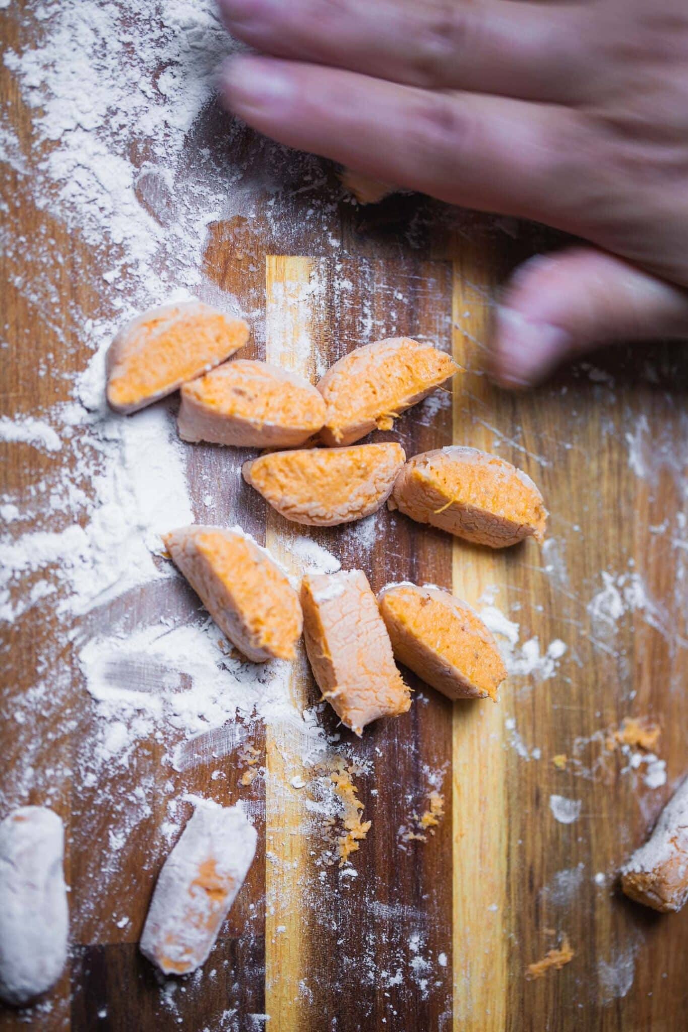 Cutting sweet potato gnocchi dough into pieces on a floured board