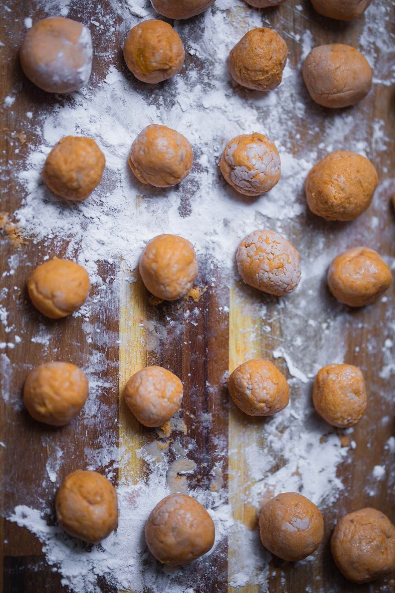 Rolled sweet potato gnocchi balls on a floured board