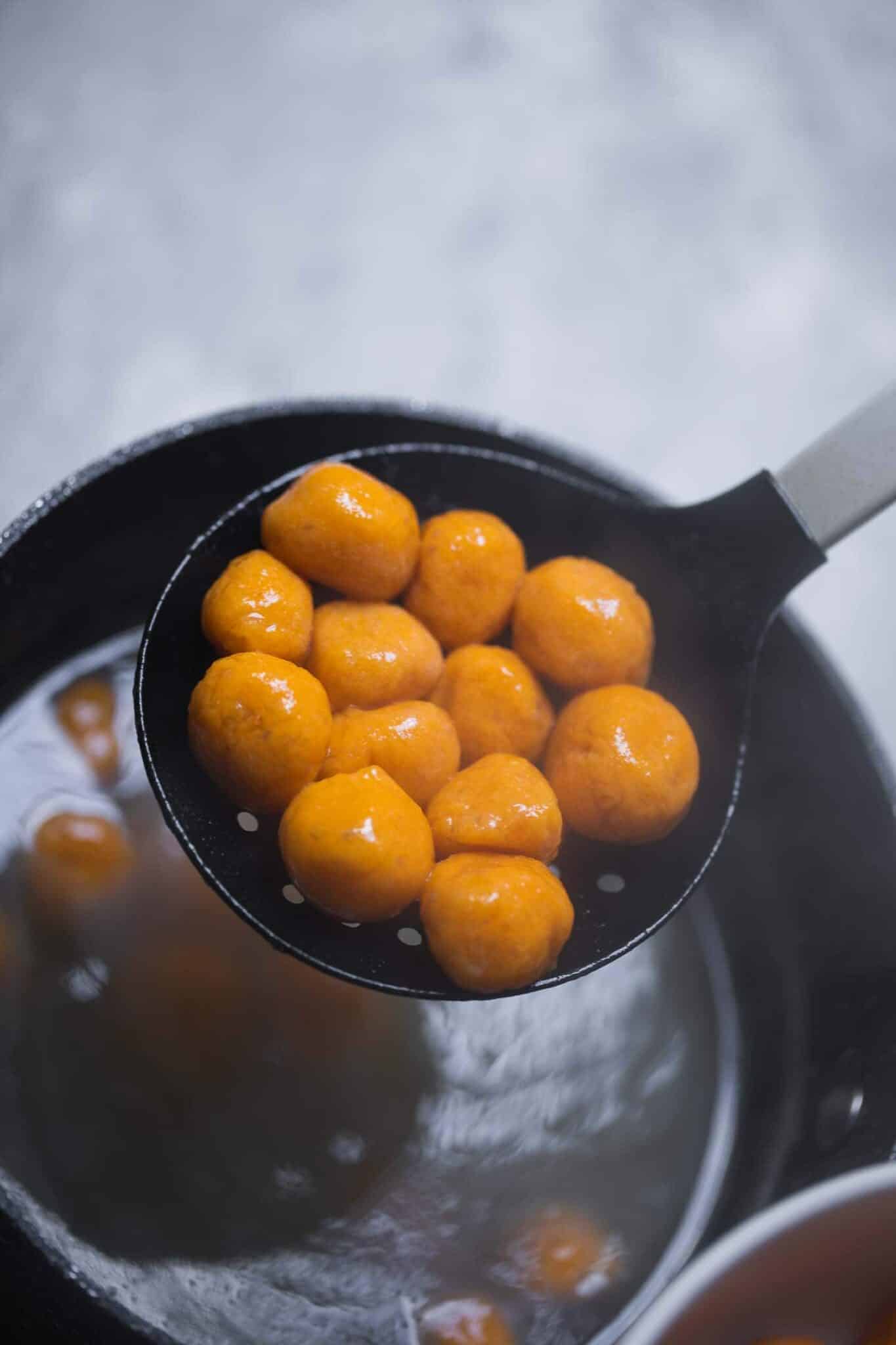 Cooked sweet potato gnocchi lifted from the pot on a slotted spoon